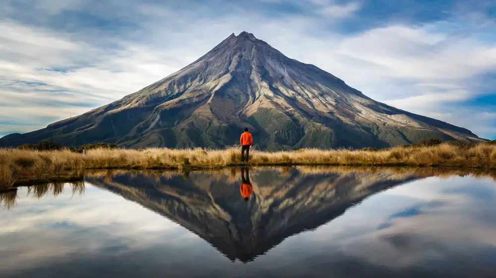 hiker looking at mountain with reflection of water